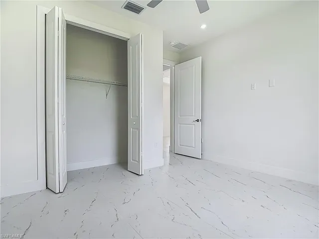 Unfurnished bedroom featuring marble look tiles, a closet, recessed lighting, and ceiling fan