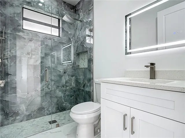 Bathroom with vanity, marble finish flooring, and a marble finish shower