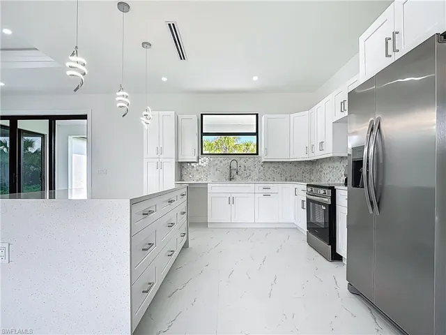 Kitchen with appliances with stainless steel finishes, backsplash, light marble finish floors, recessed lighting, and hanging light fixtures