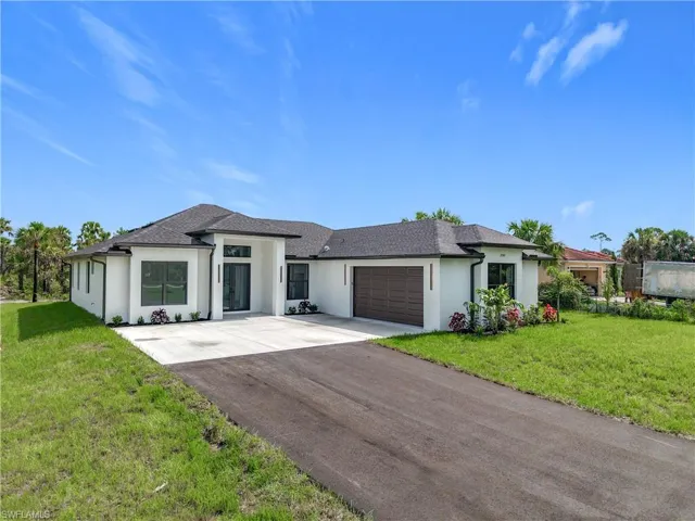 Prairie-style home with stucco siding, a garage, concrete driveway, and a front lawn
