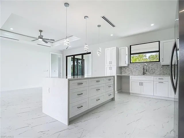 Kitchen featuring white cabinetry, a ceiling fan, hanging light fixtures, light marble finish floors, and recessed lighting