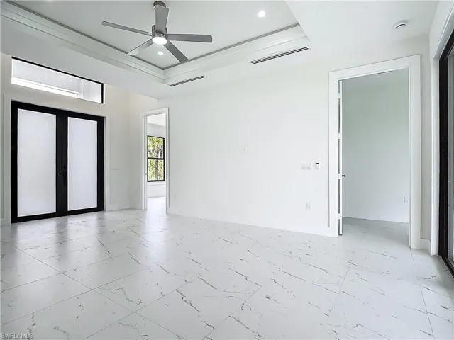 Unfurnished room featuring light marble finish flooring, ceiling fan, a raised ceiling, and recessed lighting