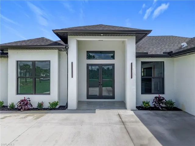 View of exterior entry with french doors, stucco siding, and roof with shingles