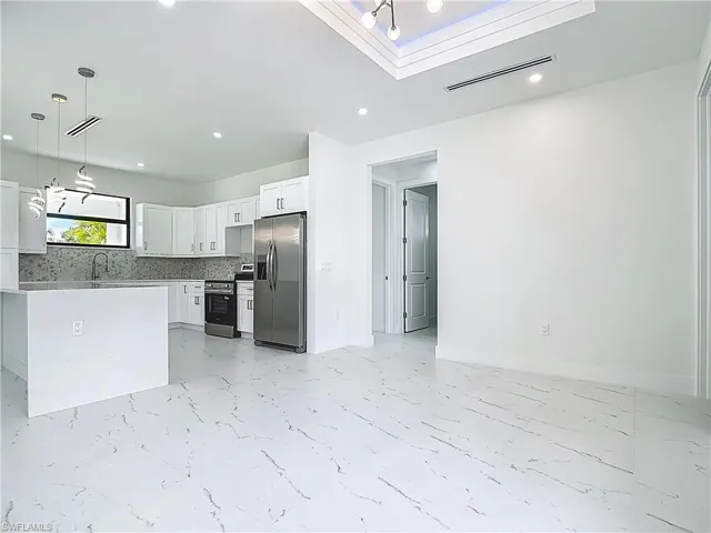 Kitchen with stainless steel appliances, light marble finish floors, white cabinets, tasteful backsplash, and recessed lighting