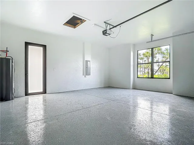 Garage with water heater, electric panel, and a garage door opener