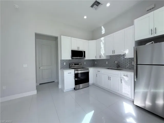 Kitchen featuring appliances with stainless steel finishes, tasteful backsplash, white cabinetry, light tile patterned floors, and recessed lighting
