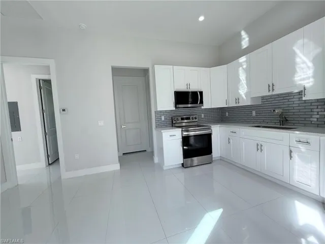 Kitchen featuring appliances with stainless steel finishes, tasteful backsplash, white cabinetry, and light tile patterned floors