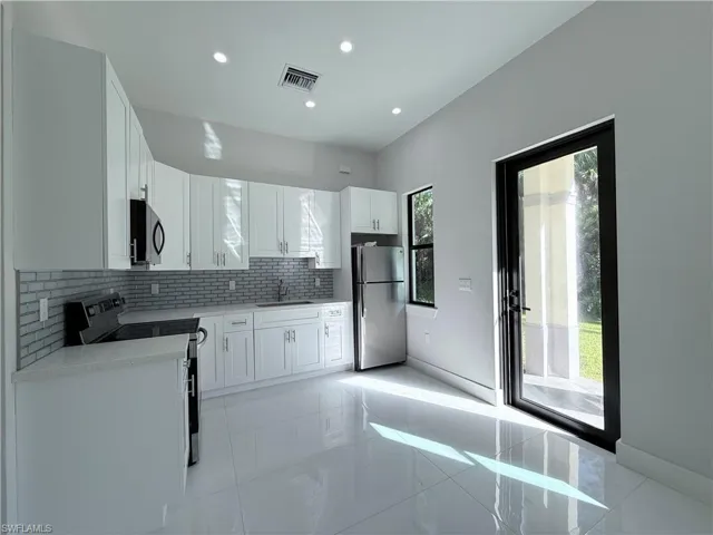Kitchen with stainless steel appliances, white cabinetry, tasteful backsplash, light stone counters, and recessed lighting