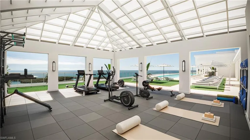 Workout area featuring high vaulted ceiling and a water view