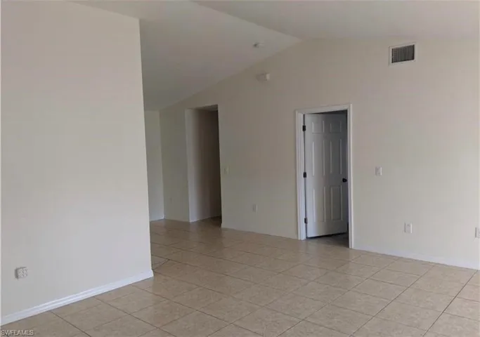 Empty room with vaulted ceiling and light tile patterned floors