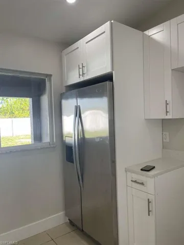 Kitchen featuring white cabinetry, stainless steel fridge with ice dispenser, and light tile patterned flooring