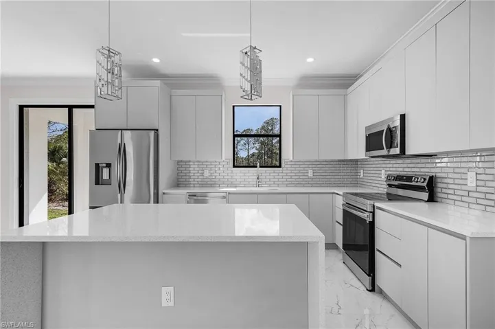 Modern kitchen featuring light gray cabinetry, stainless steel appliances, a white quartz-finish island, and a subway tile backsplash