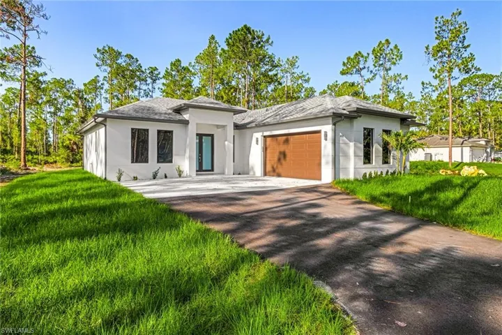 Prairie-style home with stucco siding, an attached garage, driveway, and a front yard