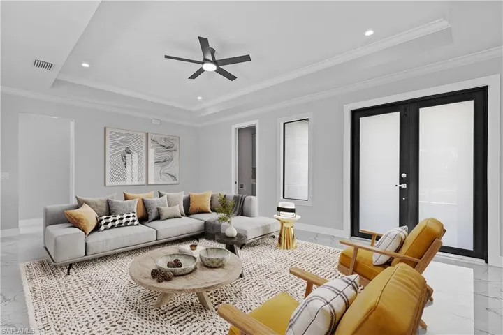 Living space featuring light-toned walls, tile flooring, and a tray ceiling with recessed lighting