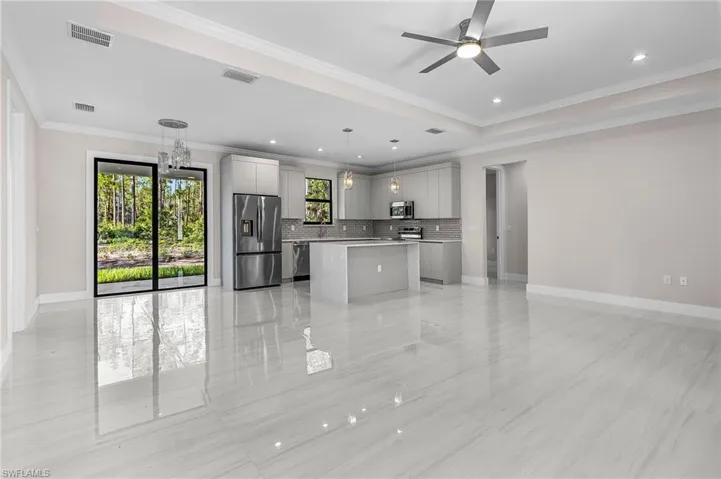 Kitchen featuring open floor plan, a kitchen island, stainless steel appliances, gray cabinets, and crown molding