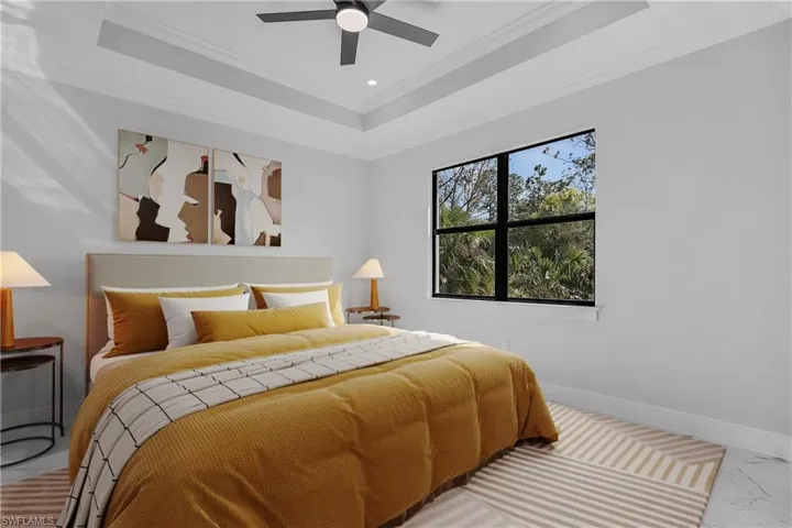 Tray ceiling with crown molding, recessed lighting, and a ceiling fan