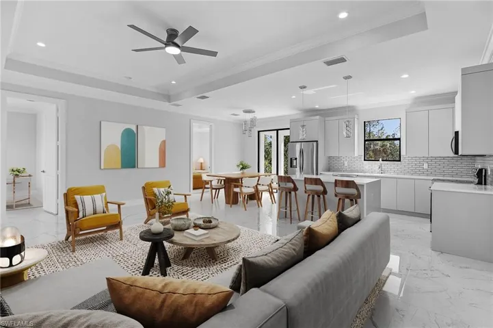 Open-concept living space featuring large format marble-look tile flooring, a tray ceiling with a modern ceiling fan, and recessed lighting