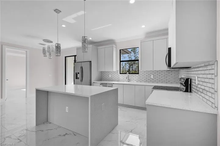 Modern kitchen featuring a waterfall island, stainless steel appliances, recessed lighting, white shaker cabinetry, and a subway tile backsplash