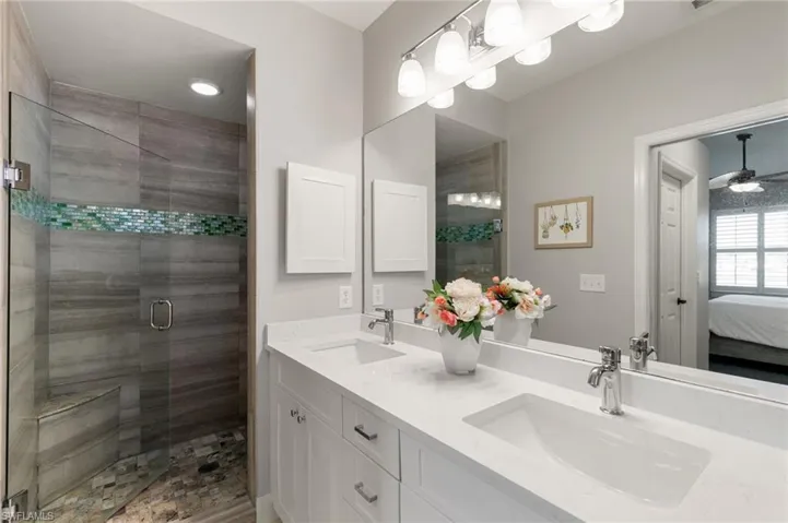 Full bath featuring double vanity, a stall shower, ensuite bathroom, and a ceiling fan