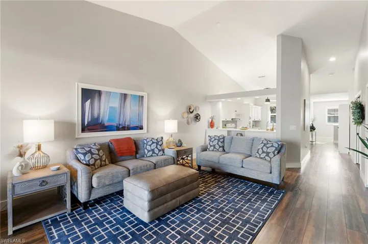 Living area with dark wood-style flooring and lofted ceiling