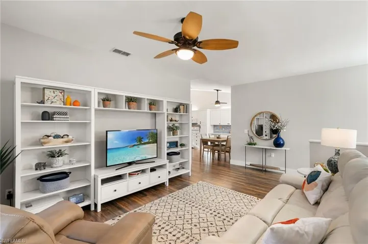 Living area featuring dark wood-type flooring and ceiling fan