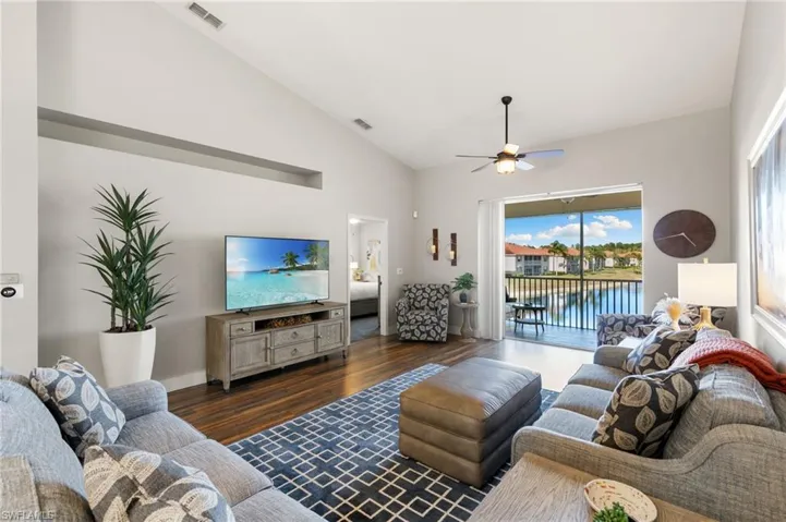 Living area with lofted ceiling, dark wood-style flooring, and a ceiling fan