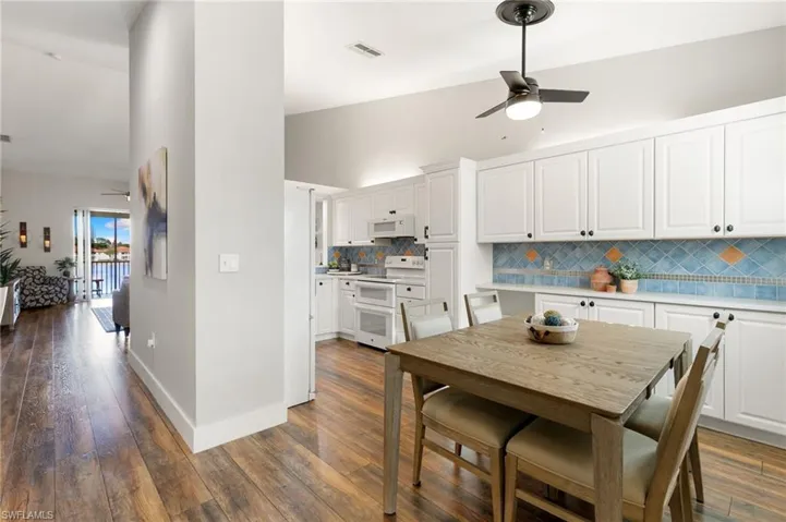 Dining room featuring a ceiling fan, dark wood-style flooring, and lofted ceiling