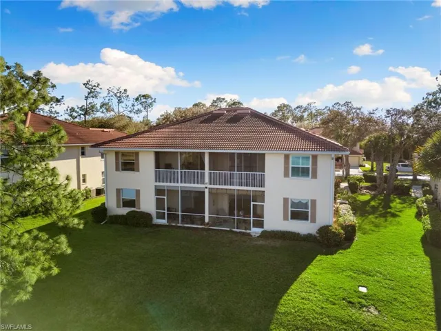 Back of property featuring a tiled roof, a sunroom, a yard, and stucco siding