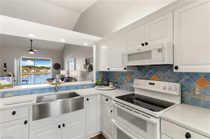 Kitchen featuring white appliances, white cabinetry, ceiling fan, lofted ceiling, and open floor plan