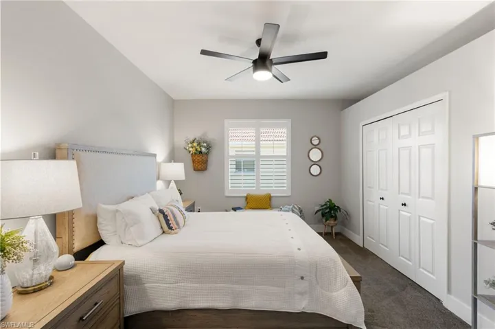 Bedroom with a closet, a ceiling fan, and dark colored carpet