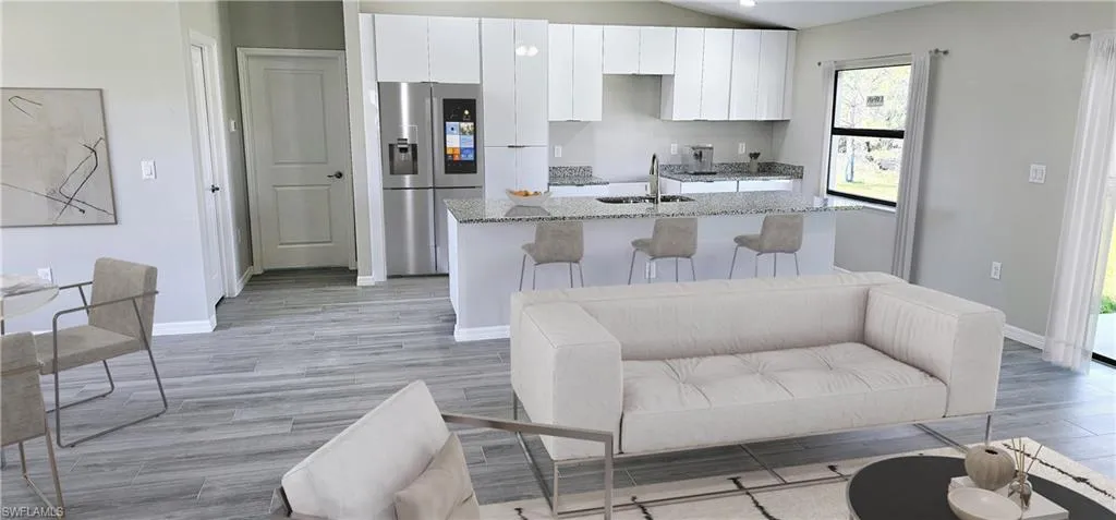 Kitchen with light wood-style flooring, white cabinets, a sink, an island with sink, and stainless steel fridge with ice dispenser