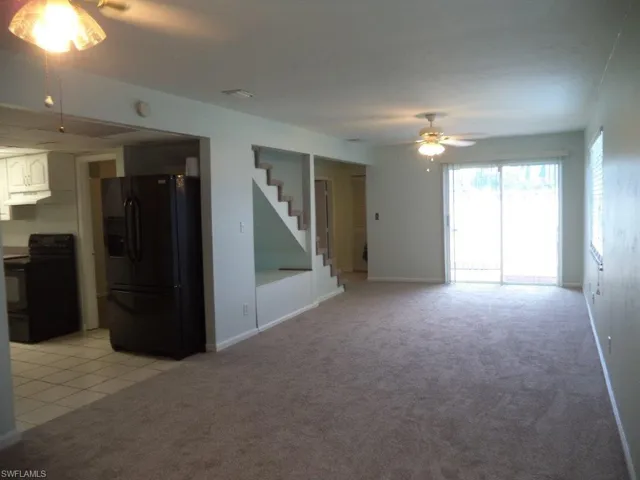 Unfurnished living room featuring light colored carpet and light tile patterned flooring