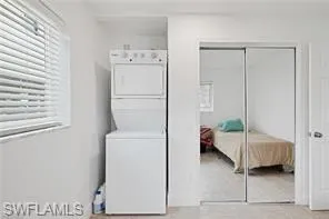 Washroom with stacked washer / dryer and healthy amount of natural light