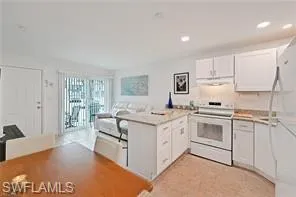 Kitchen with white range with electric stovetop, a peninsula, extractor fan, white cabinetry, and recessed lighting