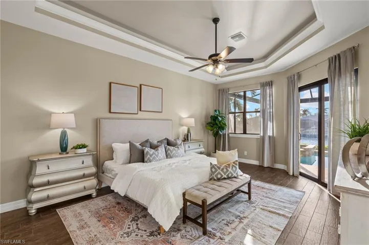 Primary Bedroom, tray ceilings, dark hardwood / wood-style flooring, and access to exterior