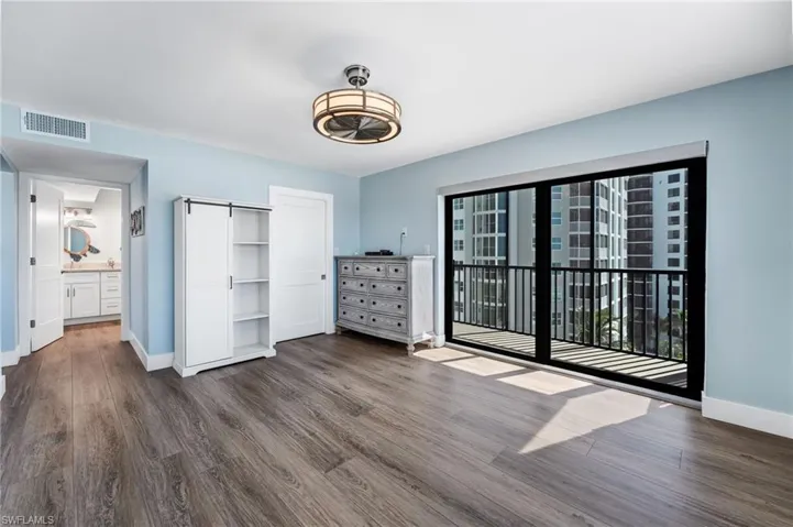 Master bedroom featuring dark wood-style floors, access to outside, and ensuite bath
