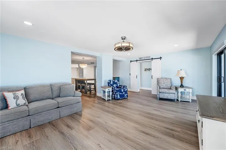 Huge Living area featuring a barn door, a chandelier, light wood-type flooring, and recessed lighting