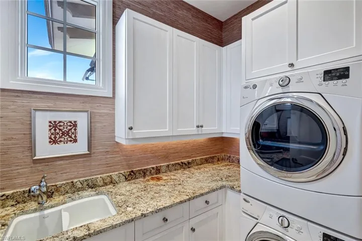 Laundry room with stacked washer / drying machine and cabinet space