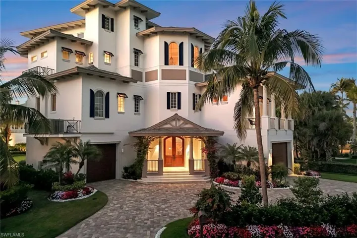 Rear view of house with decorative driveway, a balcony, stucco siding, and a garage