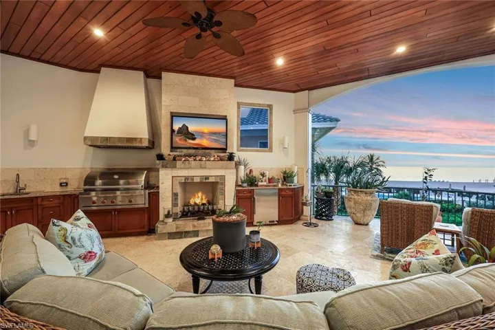 View of patio with area for grilling, a ceiling fan, and an outdoor living space with a fireplace