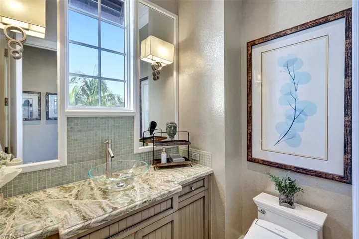 Bathroom with a textured wall, vanity, and decorative backsplash