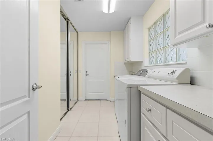 Laundry room featuring cabinets, separate washer and dryer, and light tile patterned floors