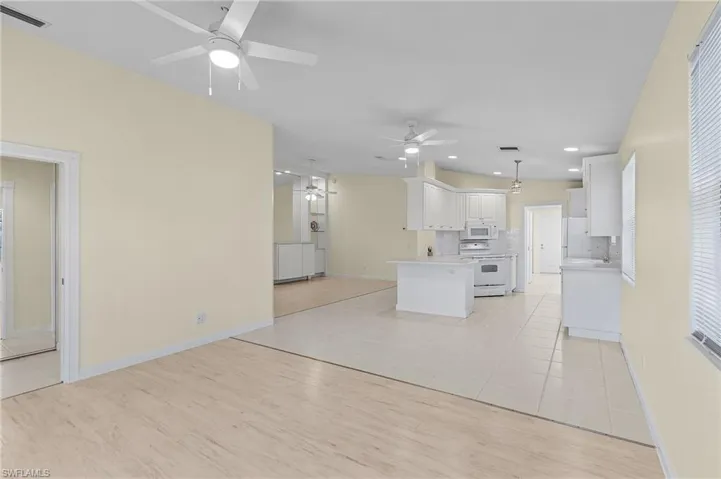 Kitchen featuring pendant lighting, white appliances, light hardwood / wood-style flooring, a kitchen island, and white cabinetry