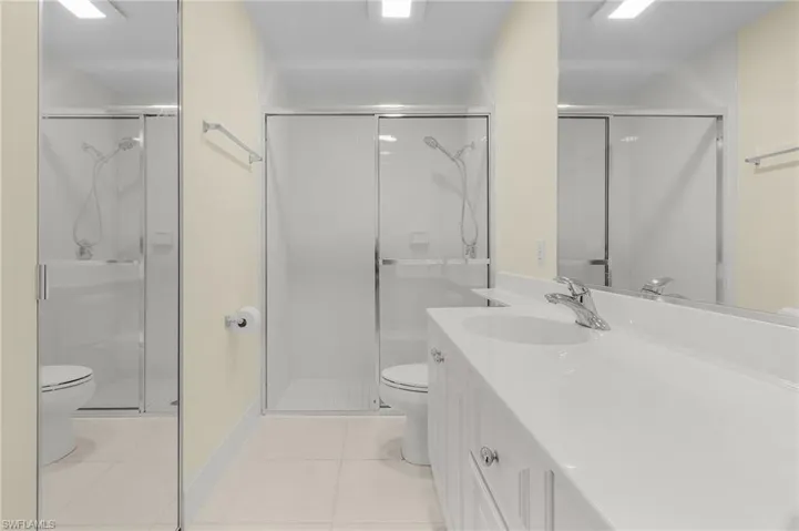 Bathroom featuring tile patterned floors, vanity, walk in shower, and toilet