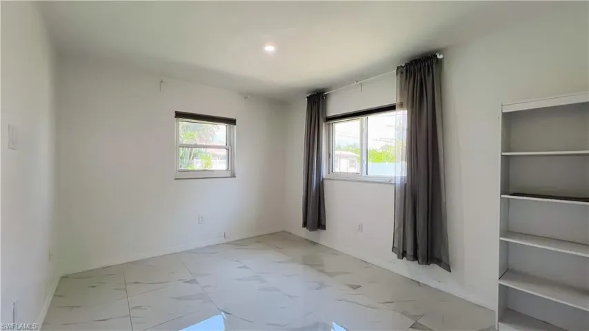 Unfurnished room with light marble finish floors, plenty of natural light, and recessed lighting