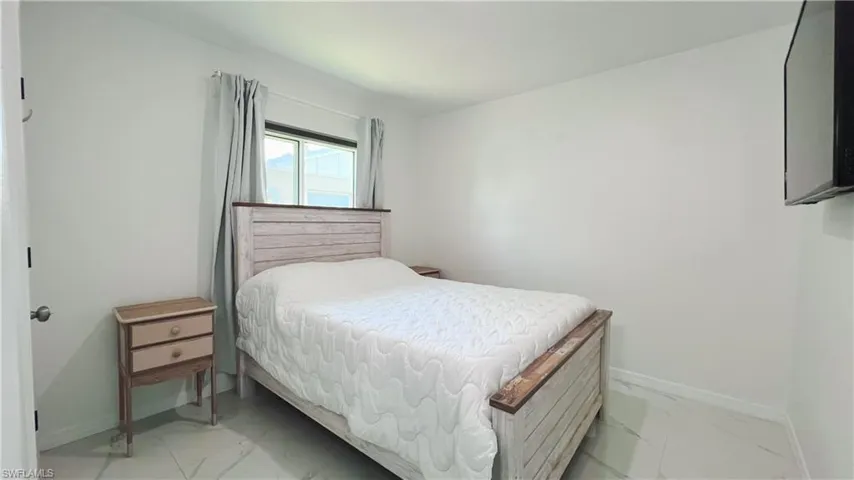 Bedroom with baseboards and light marble finish floors