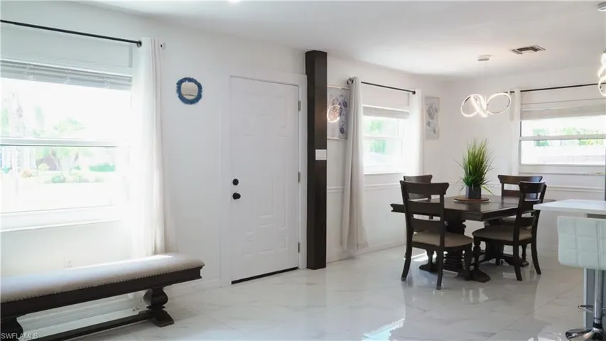Dining room featuring plenty of natural light, light marble finish flooring, and suspended lighting