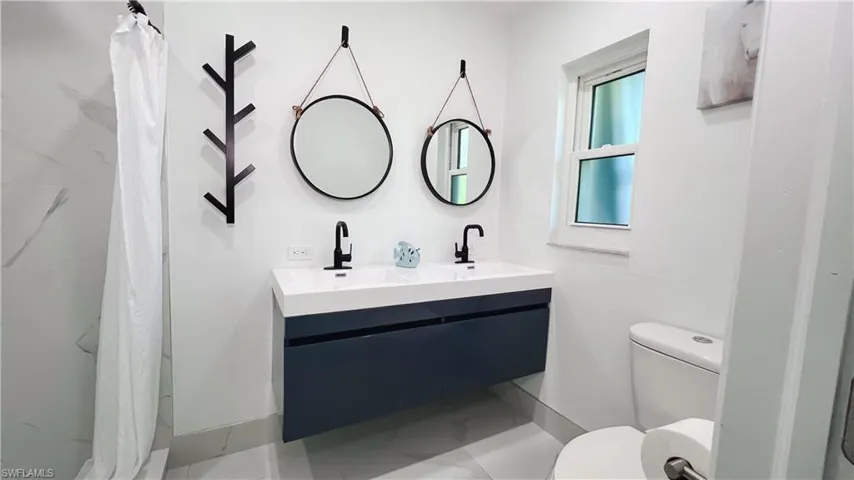 Full bath with double vanity and a shower with shower curtain