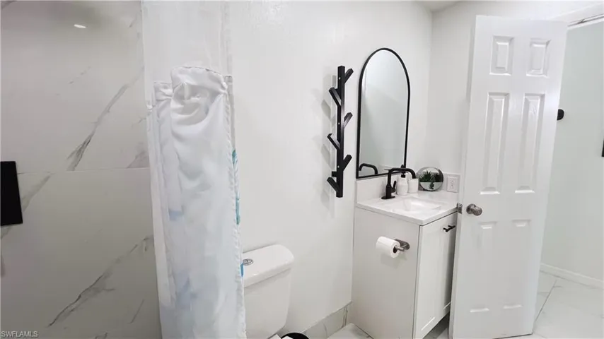 Full bath featuring curtained shower and vanity