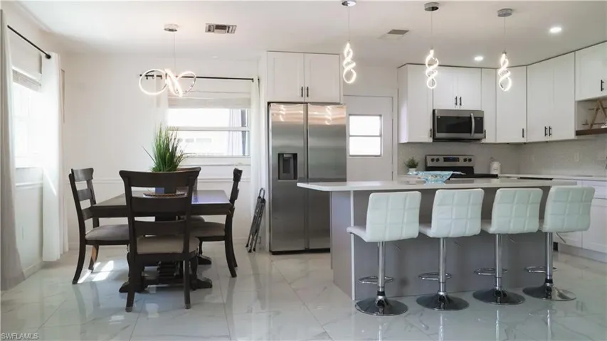 Kitchen featuring stainless steel appliances, a kitchen breakfast bar, a kitchen island, two tone cabinetry, and tasteful backsplash